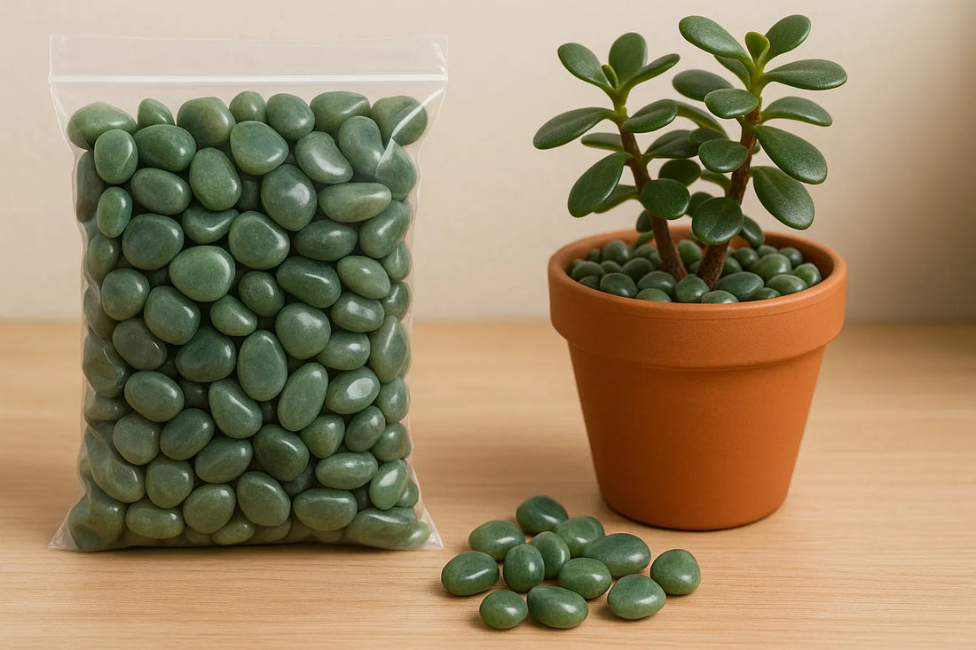 A clear bag of smooth green jade pebbles beside a terracotta pot with a jade plant, all placed on a light wooden surface indoors.